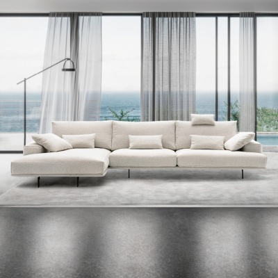 Sofá modular bege claro com almofadas numa sala com vista para o mar