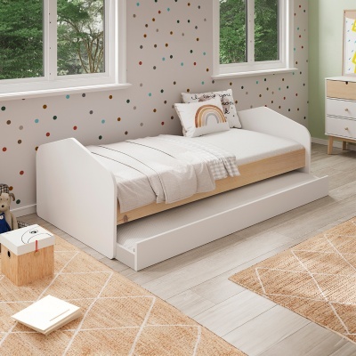 Cama desmontável branca em quarto infantil com decoração de pontos coloridos nas paredes.