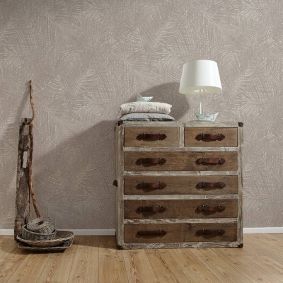Cómoda de madeira envelhecida com seis gavetas e puxadores de couro, decorada com almofadas, lâmpada branca e objeto de vidro, ao lado um cesto no chão de madeira clara