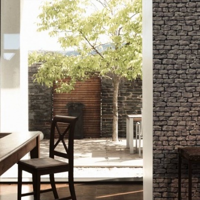 Espaço interior com mesa e cadeiras de madeira e paredes de pedra