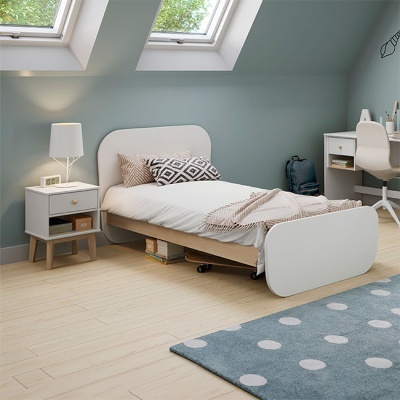 Quarto com cama individual branca e móveis claros, tapete azul com pontos brancos e janelas no teto inclinado.