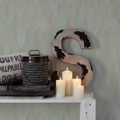 Prateleira branca com decoração que inclui tecido com texto, frasco, velas acesas e letra decorativa S