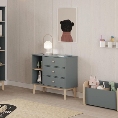 Móvel organizador cinzento com gavetas, candeeiro de mesa e decoração em parede clara