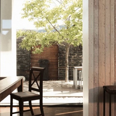 sala de jantar com mesa de madeira, cadeiras e vista para pátio com árvore