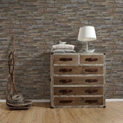 Cómoda de madeira com cinco gavetas e candeeiro branco sobre fundo de parede de pedra cinzenta