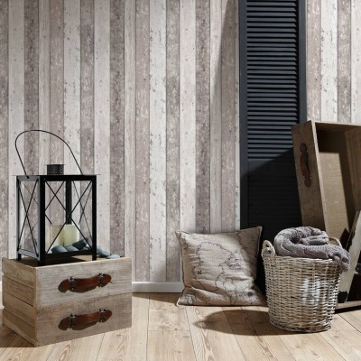 Decoração interior com lanterna preta, caixas de madeira, almofada, cesto em vime e manta sobre piso de madeira