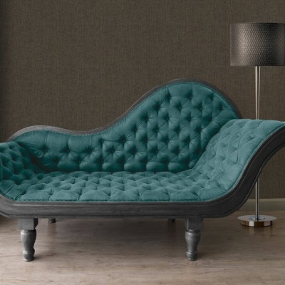 Divã azul turquesa estofado em veludo com estrutura em madeira preta numa sala com parede castanha e candeeiro de pé