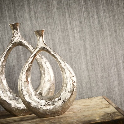 Dois vasos metálicos prateados em forma de lágrima sobre superfície de madeira