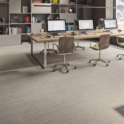 Escritório moderno com mesa comprida de madeira, cadeiras giratórias, computadores e estantes com livros