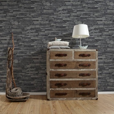 Cómoda rústica de madeira com candeeiro branco e almofadas, parede de pedra cinzenta atrás