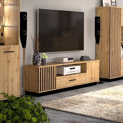 Sala com móvel de televisão em madeira, colunas de som pretas e tapete neutro.