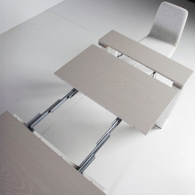 Mesa extensível de madeira clara com cadeira cinza em chão branco