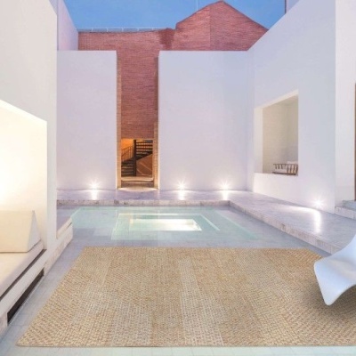 Espaço exterior com piscina retangular e tapete de ráfia em tons bege