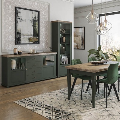 Sala de jantar com móveis de madeira verde escuro, cadeiras estofadas, mesa, aparador, estante, tapete, quadros e janelas grandes