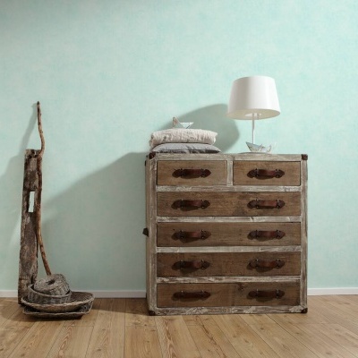 Cómoda rústica de madeira com almofadas e lâmpada ao lado de escultura de madeira