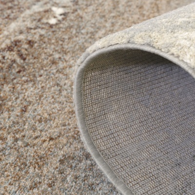 Tapete dobrado com textura macia e base trançada em tons neutros.