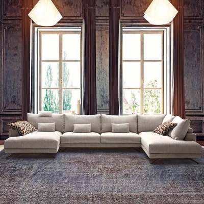 Sofá em L cinzento claro com almofadas decorativas numa sala com paredes de madeira escura e duas janelas grandes