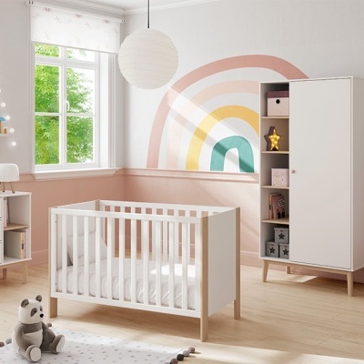 Quarto de bebé com berço branco e mobiliário em madeira clara e branca, decoração arco-íris na parede