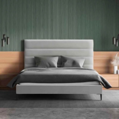 Cama estofada cinza claro com roupa cinza escuro em quarto moderno com parede verde e móveis de madeira clara