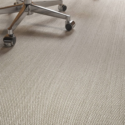 Base metálica cromada de cadeira com rodas sobre tapete bege claro texturizado