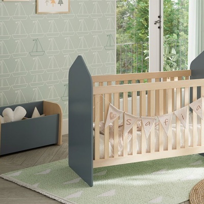 Berço infantil com decoração Safari e baú organizador num quarto iluminado