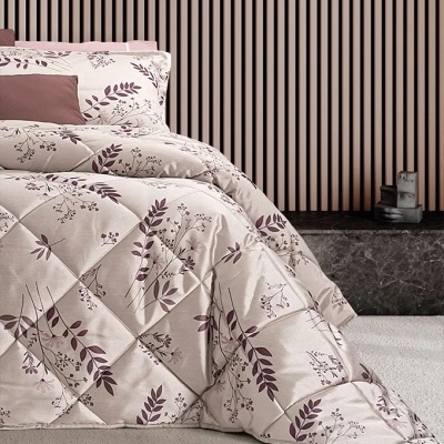 Cobre-leito acolchoado com padrão floral roxo em cama junto a parede listrada