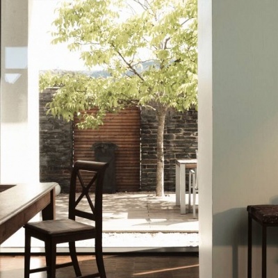 Sala de jantar com mesa e cadeiras de madeira e vista para jardim com árvore