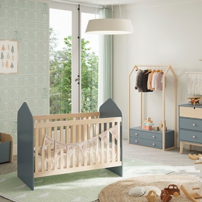 Quarto de bebé com berço de madeira com laterais azuis e decoração clara