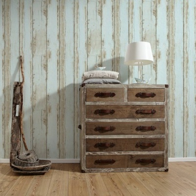 Cómoda de madeira envelhecida com gavetas e puxadores em sala com parede azul e bege e piso de madeira