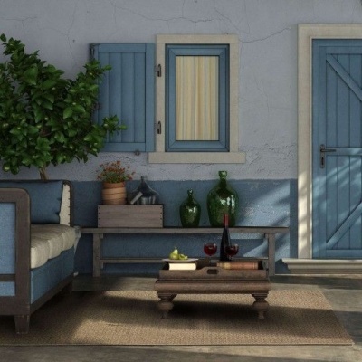 Zona de estar com sofá azul, mesa de madeira e objetos decorativos numa parede azul.