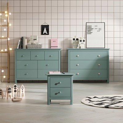Móveis verdes azulados com gavetas e decoração em parede quadriculada branca.