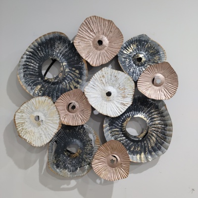 Escultura de parede decorativa em metal com várias formas circulares concêntricas e texturas enrugadas em cinza, branco e cobre.