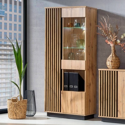 Armário alto de madeira clara com prateleiras e portas, decorado com plantas ao lado de janela grande