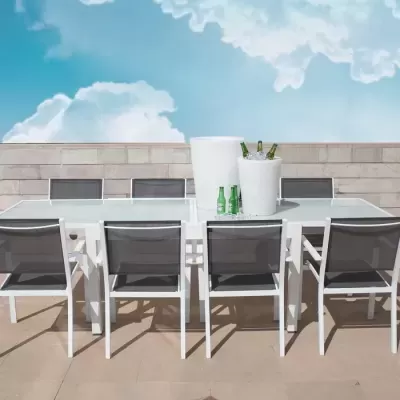 Conjunto de mesa e cadeiras de exterior em ambiente de terraço com céu azul e nuvens