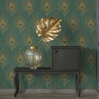 Mesa preta com jarra de vidro e folha dourada em fundo de papel de parede verde com padrão de penas douradas