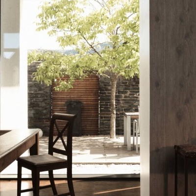 Sala de jantar com mobiliário em madeira e vista para área exterior com árvore