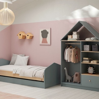 Quarto infantil com cama cinza, armário de armazenamento em forma de casa, prateleiras de madeira e decoração em tons rosa.