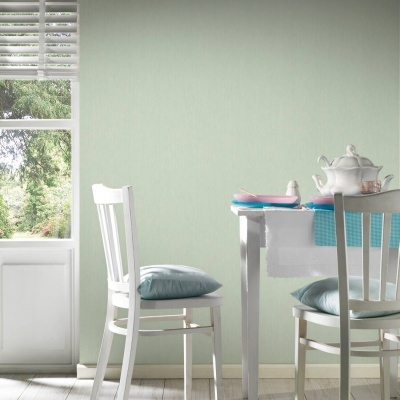 Sala de jantar com mesa, cadeiras brancas, almofadas azuis e loiça sobre a mesa