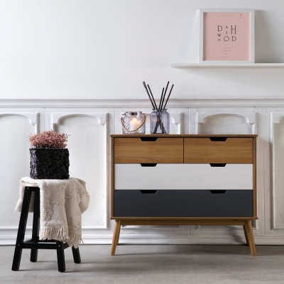 Comoda de cores castanho, branco e cinzento escuro com difusor de aromas e vela, banco preto com manta creme e planta cor-de-rosa