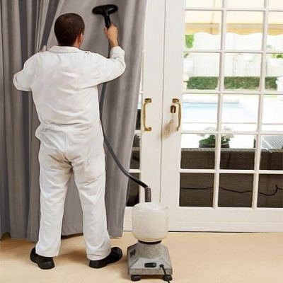 Homem a limpar cortina cinzenta com equipamento perto de porta de vidro