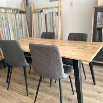 Mesa de jantar de madeira clara com quatro cadeiras cinza em sala