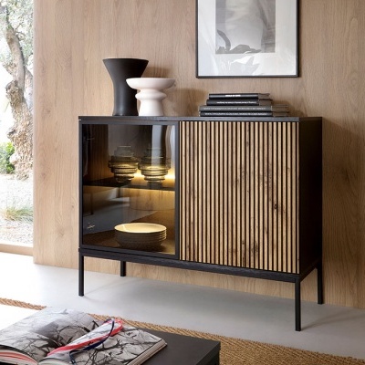 Móvel de apoio preto com porta de vidro fumado e porta de madeira ripada clara, com decoração e parede de madeira ao fundo