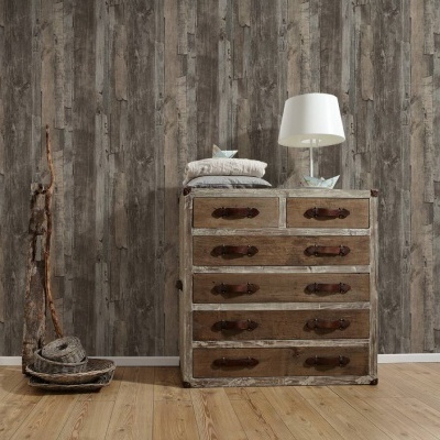 Cómoda rústica de madeira com seis gavetas, candeeiro branco e almofadas sobre chão em madeira clara