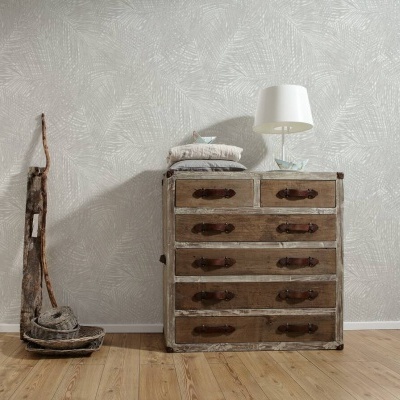Cômoda de madeira envelhecida com cinco gavetas e puxadores de couro ao lado de decoração rústica e lâmpada branca em chão de madeira clara