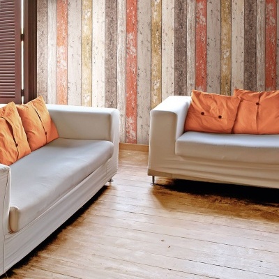 Sofás brancos com almofadas laranja e parede listrada colorida