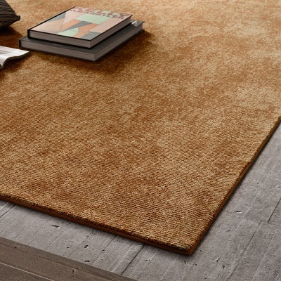 Tapete castanho texturizado sobre pavimento de madeira clara com livros em cima