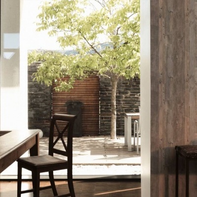 Sala de jantar com mesa de madeira escura, cadeiras e vista para jardim