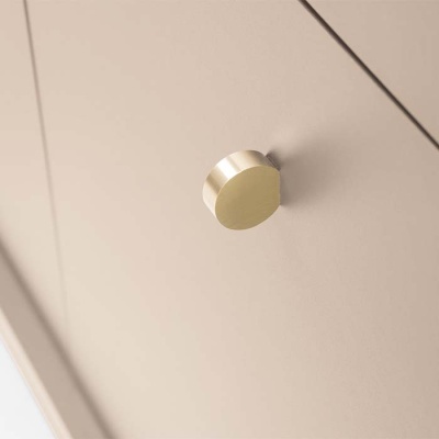 Botão redondo dourado numa porta ou gaveta creme