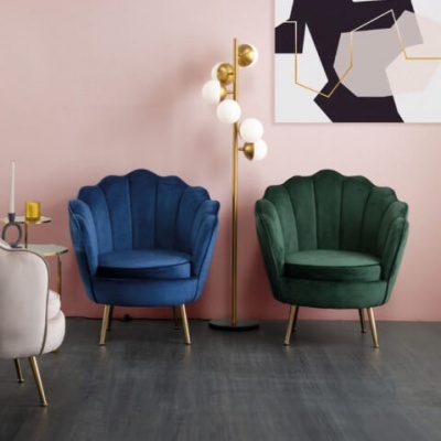 Três cadeirões coloridos em veludo com pernas douradas numa sala decorada com candeeiro de pé e quadro abstracto.