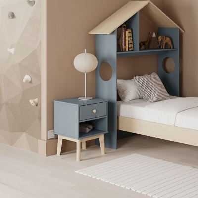 Quarto infantil com cama em formato de casinha azul e bege, criado-mudo azul com candeeiro branco, almofada riscada, livros, elefante decorativo e parede de escalada